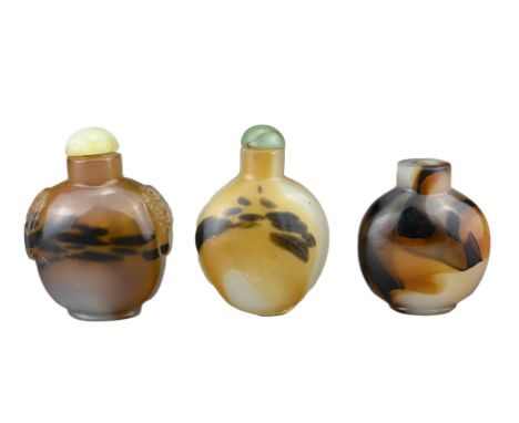 THREE CHINESE SNUFF BOTTLES. Comprising two agate bottles with green stone stoppers, one with caved mask and ring handles. To