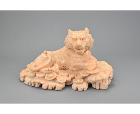 A CHINESE VINTAGE STONE CARVING OF A TIGER, 20TH CENTURY. Resting on cash coins and ingots. 28cm length.