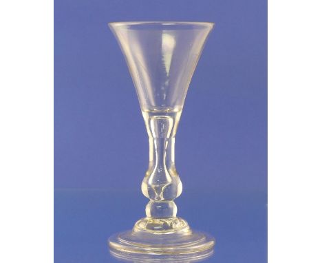 An early 18thC baluster wine glass, c.1720, with trumpet bowl, on a drawn stem enclosing a tear, with swelling and base knop,