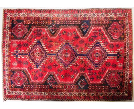 Two vintage 20th century Persian Islamic floor carpet rugs. A bokhara in a red ground with geometric central medallions, enca