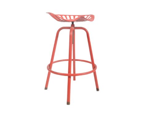 A retro 20th century cast iron tractor seat stool / bar chair of typical form raised on four tubular supports united by a tub