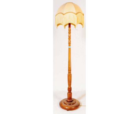 A vintage mid 20th century turned oak floor standing standing lamp. With floral yellow tiffany dome shade with tassels atop a