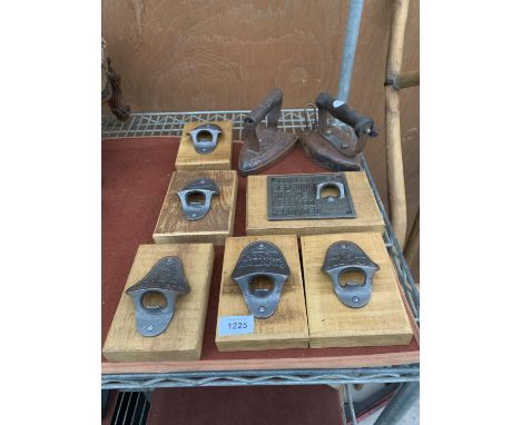 AN ASSORTMENT OF NAMED BOTTLE OPENERS WITH WOODEN WALL MOUNTING PLINTHS AND TWO VINTAGE FLAT IRONS 