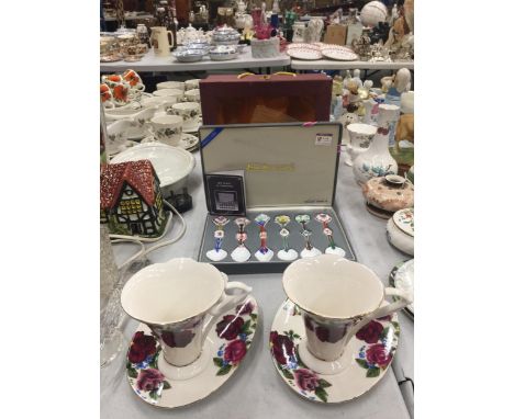 A XINJIE CERAMICS BOXED CUP AND SAUCER SET WITH EASEL SHAPED SAUCERS AND A BOXED SET OF SIX CERAMIC ART SPOONS 