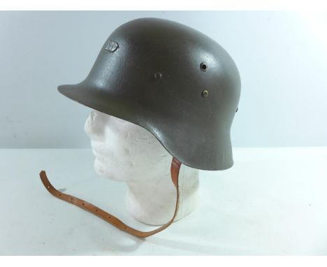 A GREEN PAINTED METAL GERMAN HELMET AND LINER 