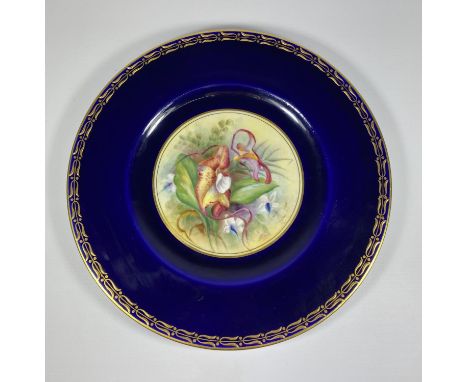 A ROYAL WORCESTER HAND PAINTED PORCELAIN PLATE, SIGNED J.PRICE DEPECITING FLOWERS AGAINST A COBALT BLUE GROUND WITH GILT DESI