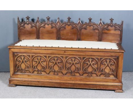 A Victorian Panelled Walnut Box Seat in the Pugin Manner, with carved Gothic arch back, the seat with moulded edge and uphols