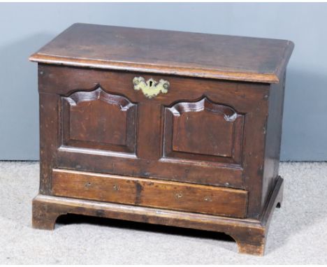 An 18th Century Welsh Oak Coffer Bach, the plain lid with moulded edges, the front with twin shaped fielded panels, fitted on