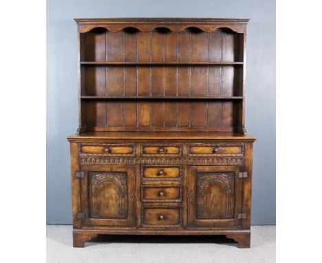 A Panelled Oak Dresser of "18th Century" Design, the upper part with moulded cornice above shaped apron, fitted two open shel