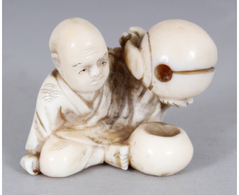 A SIGNED JAPANESE MEIJI PERIOD IVORY NETSUKE OF A YOUNG MONK, holding aloft a temple bell and with a begging bowl at his feet