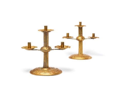 A pair of Northern European repoussé brass three light candelabra, late 18th/early 19th century, each with a raised central s