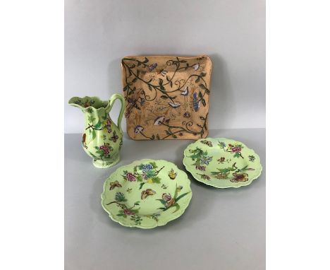 Square unglazed dish decorated with glazed insects and plants in relief, along with two pale green ceramic plates and a jug d