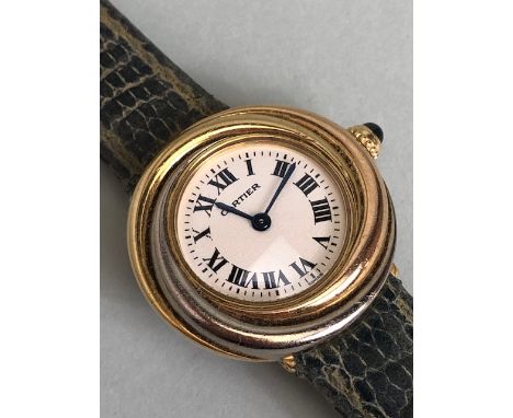 Cartier. A lady's 18K gold Cartier quartz wristwatch of swirl form Model: 2357 Trinity, Roman Numerals with hidden signature 