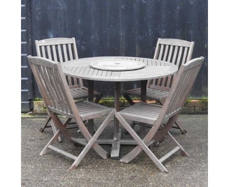 A teak garden table, 109cm diameter, together with four folding chairs (5)