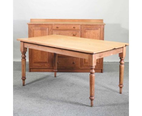 A modern pine dining table, on turned legs, together with a light oak sideboard containing a row of short drawers, flanked by