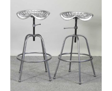 A pair of painted metal tractor seat stools, with revolving seats