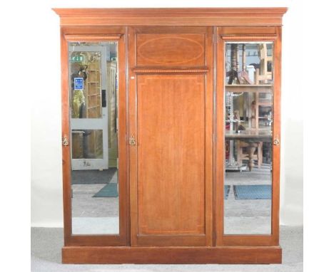 An Edwardian mahogany triple wardrobe, the central panelled door, flanked by a pair of mirrored doors,183w x 54d x 214h cmCon