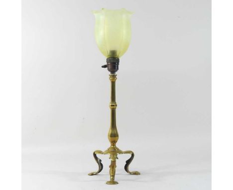 An early 20th century Arts and Crafts brass table lamp, in the manner of WAS Benson, on three stylised feet, with a yellow op
