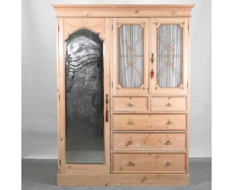 An Edwardian stripped pine combination wardrobe, enclosed by a mirrored door, a pair of glazed doors and drawers below153w x 