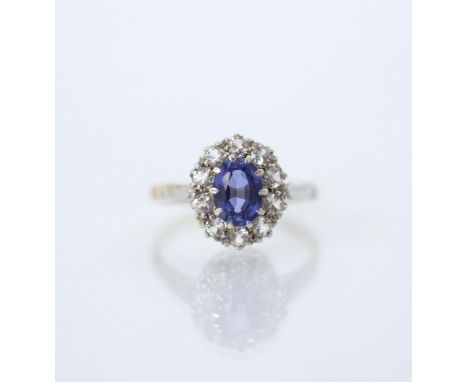 An Edwardian style synthetic sapphire cluster ring, the oval cut blue stone within surround of ten white stones in white meta