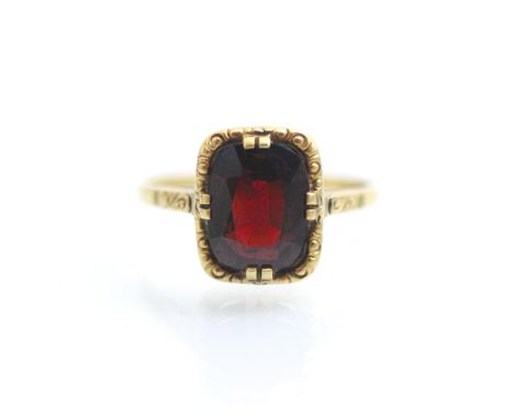 A 19th century style untested garnet ring, the central cushion cut stone within yellow metal carved mount leading to conformi