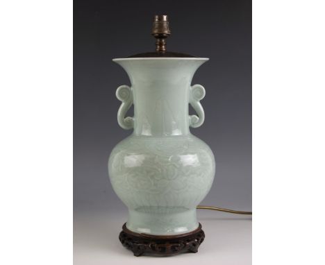 A Chinese porcelain celadon lamp base, with all over scrolling leaf and vine decoration, hardwood base and shade, 61cm high o