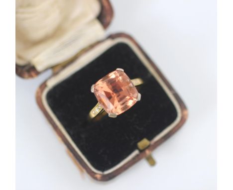 An early 20th century untested pink topaz and diamond ring, the cushion cut peach coloured stone within white metal claw sett