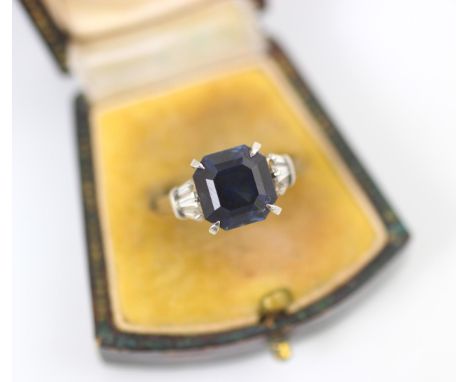 An Art Deco style diamond and untested sapphire ring, the central emerald cut untested sapphire claw set with three fancy cut