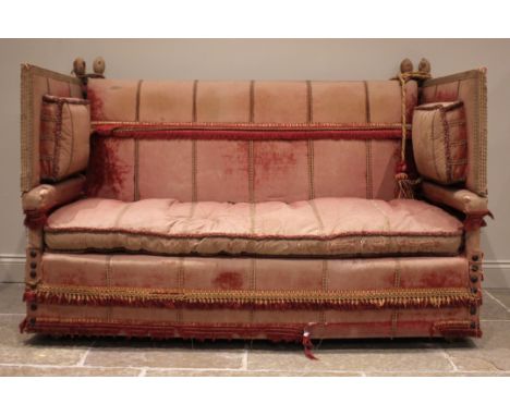 An 18th century knoll or Knole sofa, in pink velour fabric applied with tassel fringes, the straight back rest extending to d