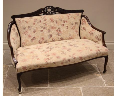 An Edwardian mahogany framed sofa, re-upholstered in floral fabric, the carved oval open work crest extending to an out swept