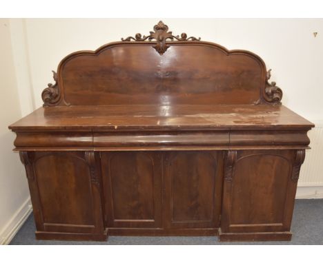 An early Victorian mahogany sideboard, with shaped arched top, three frieze drawers above four panel drawers revealing a fitt