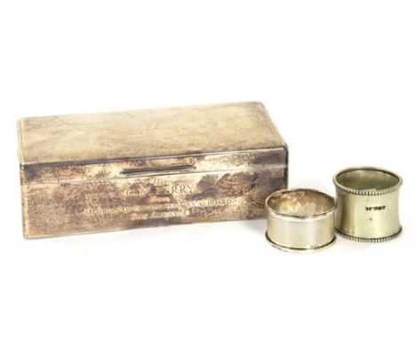 AN ELIZABETH II SILVER CIGARETTE BOX, THE LID ENGINE TURNED, CEDAR LINED, 17CM W, LONDON 1964 AND TWO SILVER NAPKIN RINGS