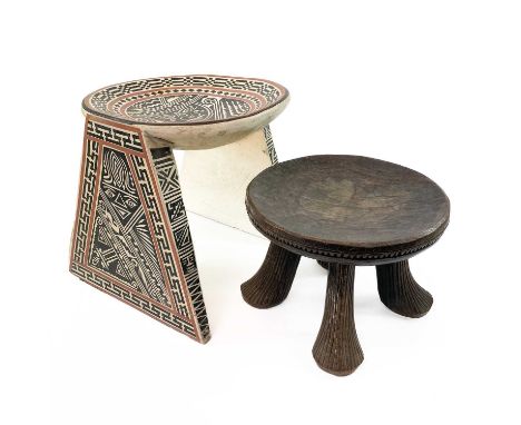 An African carved circular tripod stool. Height 20cm, together with another stool. (2)