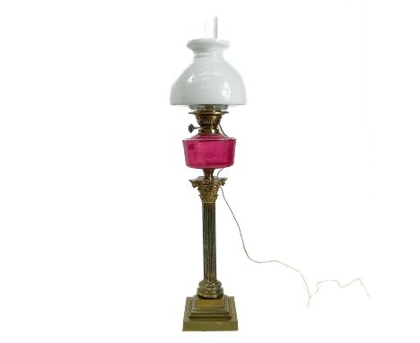 A converted Victorian oil lamp with cranberry glass well and white glass shade. Height 88cm.