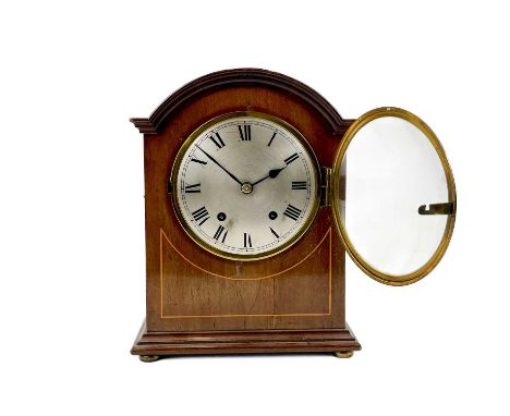 An Edwardian mahogany dome top mahogany and line inlaid mantel clock. With a circular silvered dial, striking on twin gongs, 