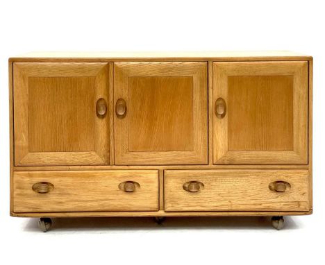 An Ercol Windsor light elm sideboard. With a double cupboard and single cupboard revealing a single shelf and cutlery drawer 