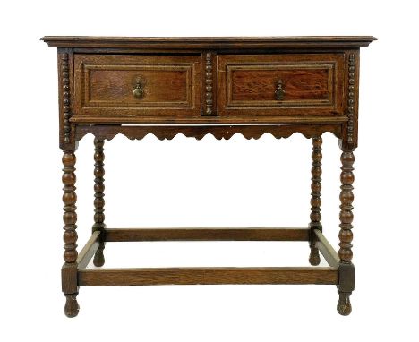 An early 20th century oak side table . With two short drawers, a shaped apron on bobbin turned supports and plain stretcher, 