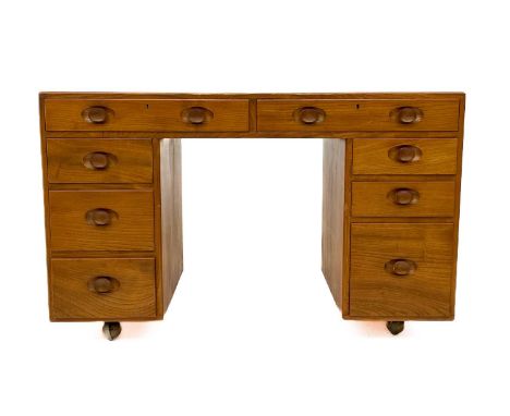An Ercol Windsor light elm kneehole desk. With an arrangement of eight drawers on original castor wheels, height 73cm width 1