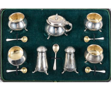 An Edwardian seven piece silver condiment comprising four salts of baluster form supported on three legs together with two pe