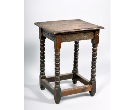 A late 17c/early 18c oak occasional table of pegged construction with bobbin turned legs and moulded stretcher rails, carved 