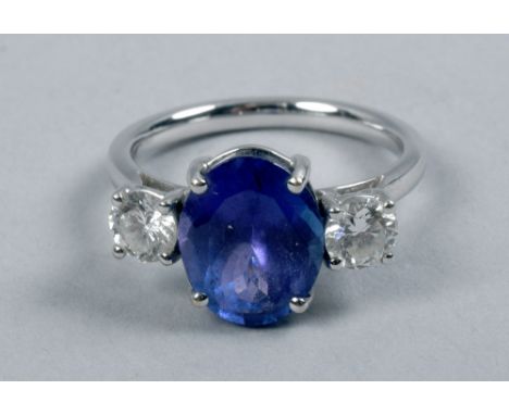 An 18ct white gold ring set with one central sapphire flanked by two diamonds in a raised setting.