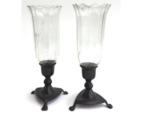 A pair of early 20th century bronze candlesticks, each on triform base with paw feet, and glass hurricane shade with scallope