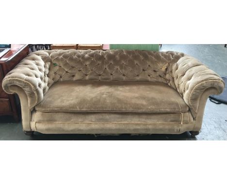 A button back Chesterfield sofa, upholstered in green, on brass casters 