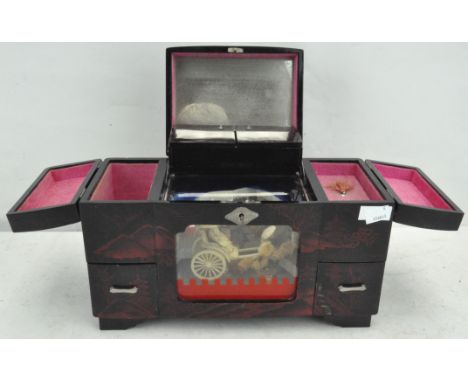 A vintage Japanese lacquer music/jewellery box with bone figures of a lady in a carriage pulled by an assistant behind a glas