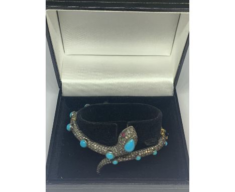 A GOLD AND WHITE GOLD SNAKE BANGLE ENCRUSTED WITH DIAMONDS, RUBY EYES AND BLUE NAJAVO STONES 