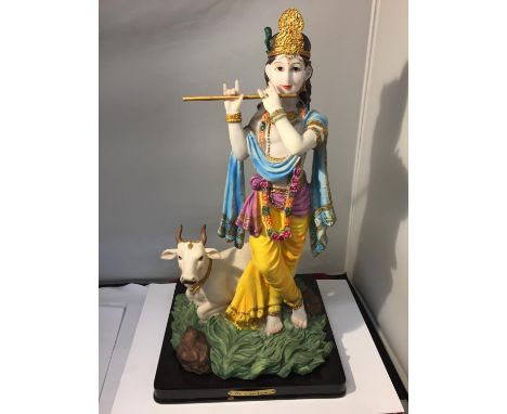 A CERAMIC FIGURE OF AND INDIAN LADY WITH A FLUTE AND A COW 