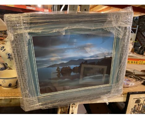 A FRAMED AND MOUNTED PRINT OF A LANDSCAPE LAKE SCENE AT DUSK 
