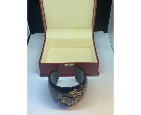 A HEAVY BLACK BANGLE WITH A GOLD AND DIAMOND DECORATION IN THE FORM OF SAGITTARIUS 