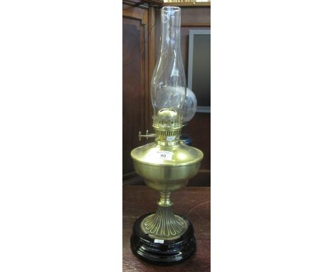 Early 20th century brass double burner oil lamp with brass reservoir on fluted pedestal and ceramic base, clear glass chimney