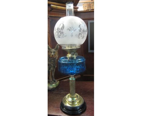 Early 20th century brass double burner oil lamp with coloured glass reservoir on brass pedestal, frosted glass shade and clea